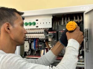 electrician reviewing certification documents on desk with electrical panel background